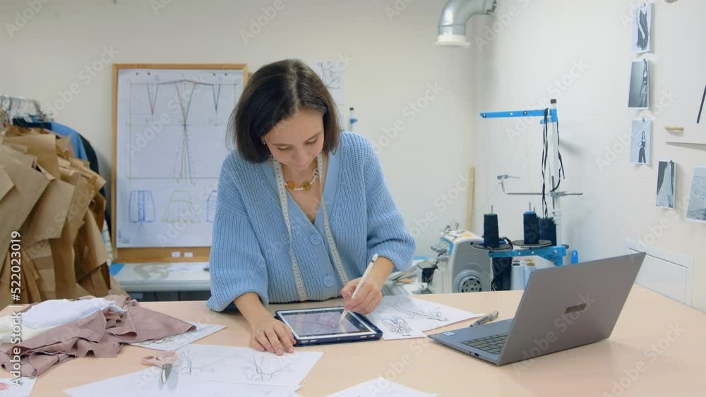 4K. A young woman working in a clothing store. A fashion designer makes sketches on a tablet. 4K. A young woman working in a clothing store. A fashion designer makes sketches on a tablet.