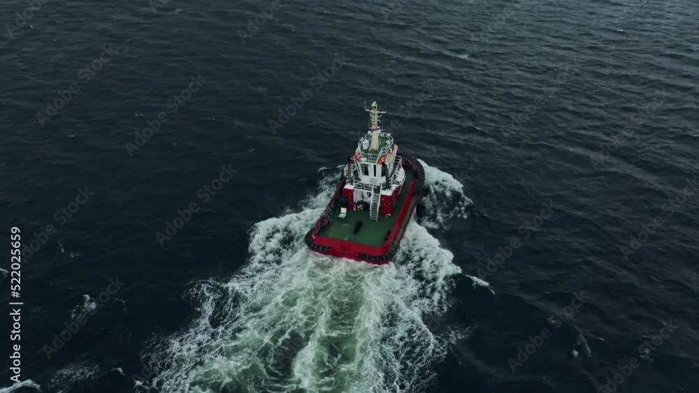 Tug Boat goes to the open sea in stormy weather to help ship maneuver aerial view. Tugboat follows large container ship into open sea in heavy rain and storm. Drone shot back panning over the ocean. Tug Boat goes to the open sea in stormy weather to help ship maneuver aerial view. Tugboat follows large container ship into open sea in heavy rain and storm. Drone shot back panning over the ocean.