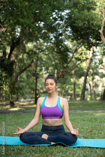 Young Asian healthy woman doing yoga in the park.