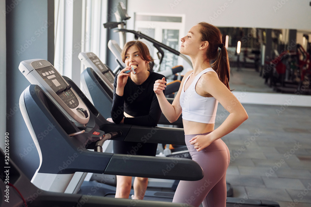 Running on the racetrack. Two women in sportive clothes have fitness day in the gym together Running on the racetrack. Two women in sportive clothes have fitness day in the gym together