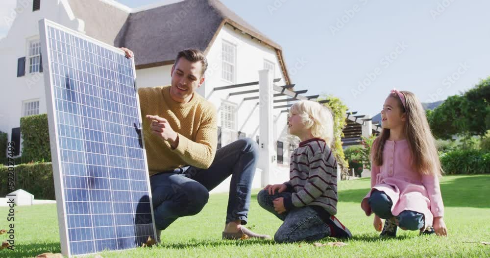 Video of happy caucasian father explaining solar panel to son and daughter in sunny garden Video of happy caucasian father explaining solar panel to son and daughter in sunny garden
