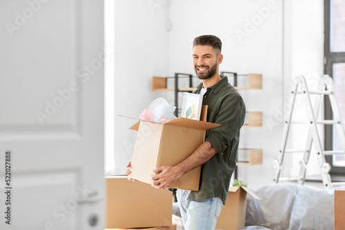 moving, people and real estate concept - happy smiling man holding box with stuff at new home