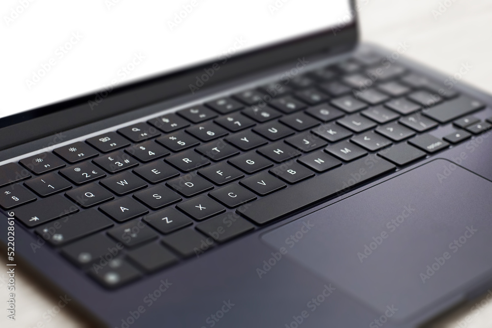 Modern, slim, backlit laptop membrane keyboard. Black keyboard large board. Selective focus.