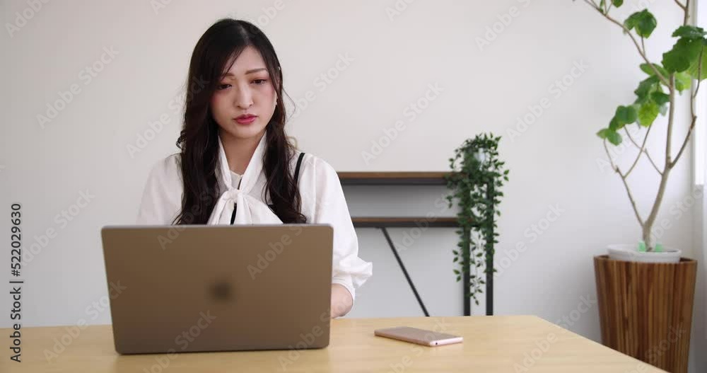 A Japanese woman checking smartphone by remote work in the small office A Japanese woman checking smartphone by remote work in the small office