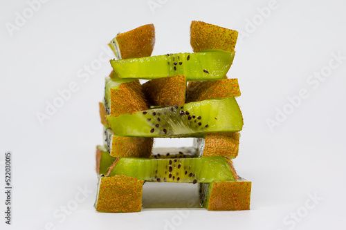 Macro photo of overlapping kiwi pieces. Tower of kiwi pieces. Jenga game created with pieces of kiwi. Citric fruits. Tropical fruits.