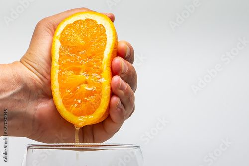 Macro photo of an orange squeezed with a hand. Orange juice. Side photo. Citrus fruit juice. Natural juices.