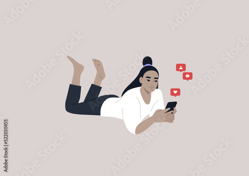 A young female Asian character lying on their stomach and checking their mobile phone notifications