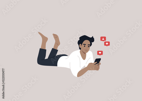 A young male Caucasian character lying on their stomach and checking their mobile phone notifications