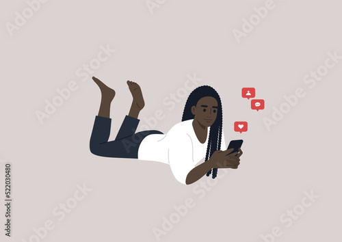 A young female African character lying on their stomach and checking their mobile phone notifications
