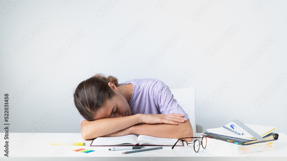 A tired student sleeps on a notebook on the table - before the exam