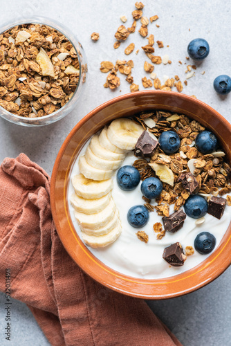 Yogurt granola bowl with blueberries, banana and chocolate. Top view