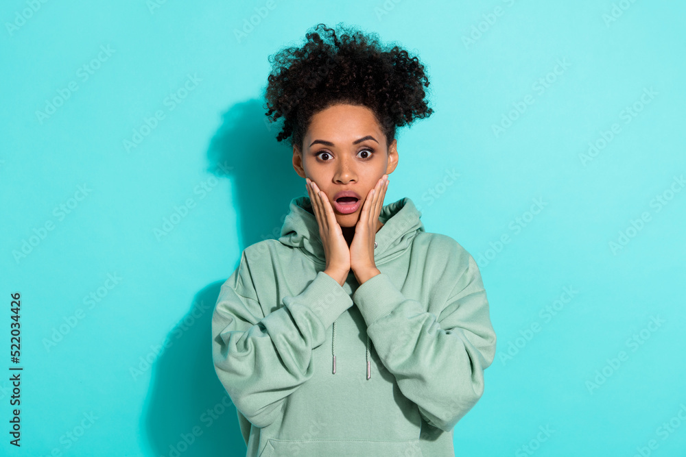 Portrait of impressed confused person arms touch cheeks open mouth isolated on vibrant teal color background Portrait of impressed confused person arms touch cheeks open mouth isolated on vibrant teal color background