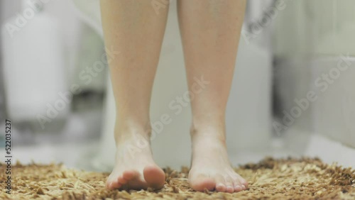 Woman is sitting on the toilet in the home bathroom. Legs close-up. Concept of constipation and diarrhea. photo