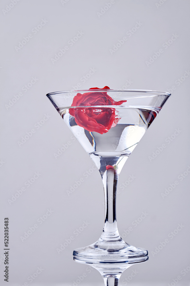 Vertical shot of cocktail with red flower. Transparent alcoholic drink. Vertical shot of cocktail with red flower. Transparent alcoholic drink.