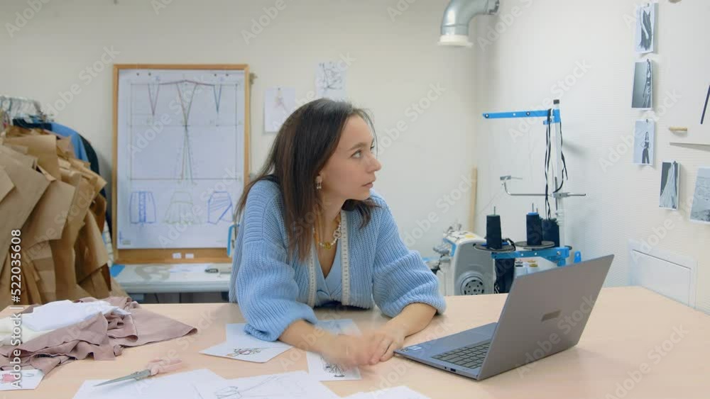4K. A young woman working in a clothing store. A tired female fashion designer makes sketches on paper. 4K. A young woman working in a clothing store. A tired female fashion designer makes sketches on paper.