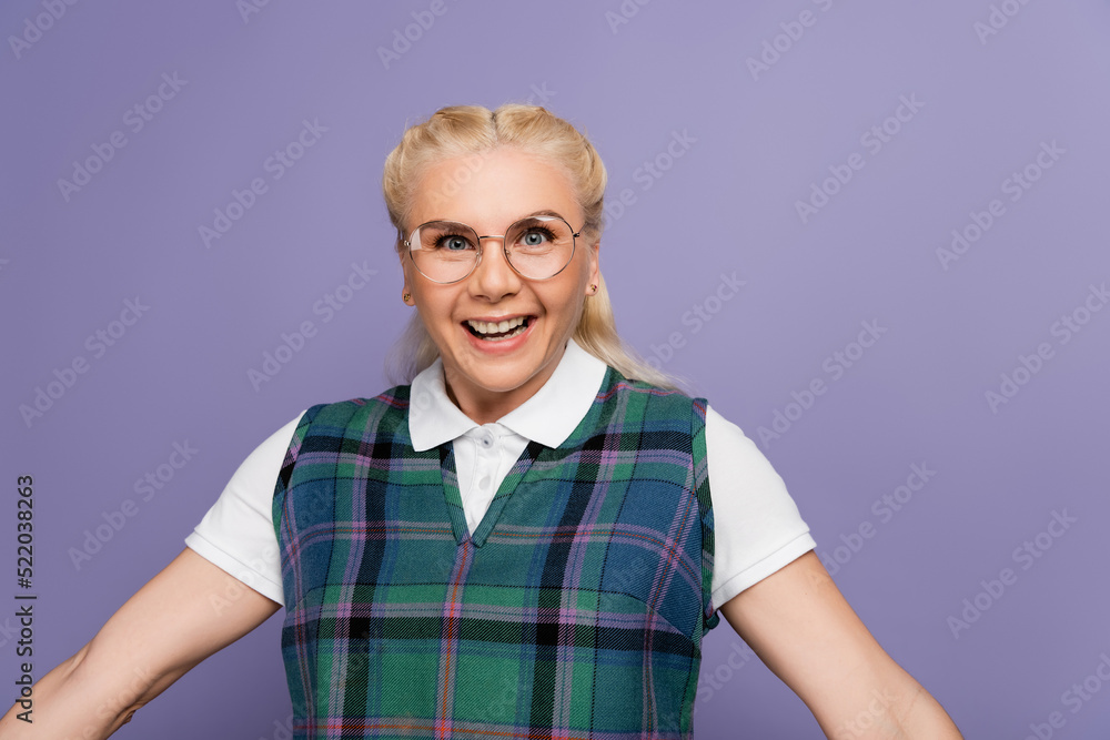 Cheerful student in eyeglasses looking at camera isolated on purple Cheerful student in eyeglasses looking at camera isolated on purple
