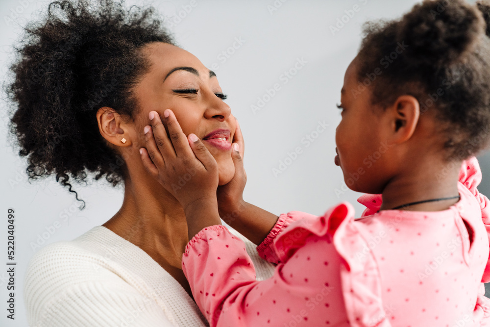 African american happy woman smiling and hugging her daughter at home African american happy woman smiling and hugging her daughter at home