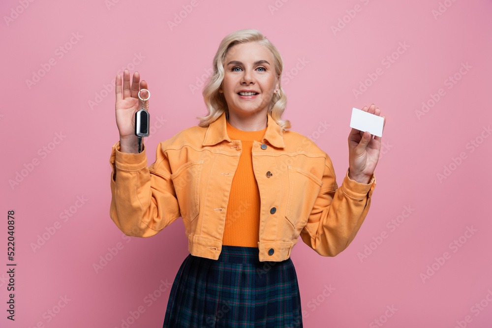Smiling woman holding car key and driving license isolated on pink Smiling woman holding car key and driving license isolated on pink