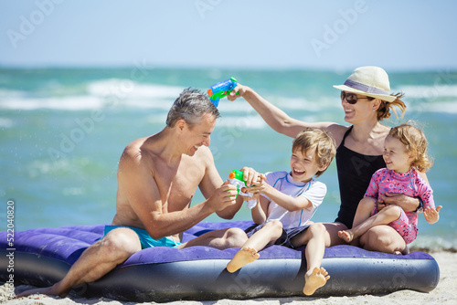 Happy family of four having fun on the beach