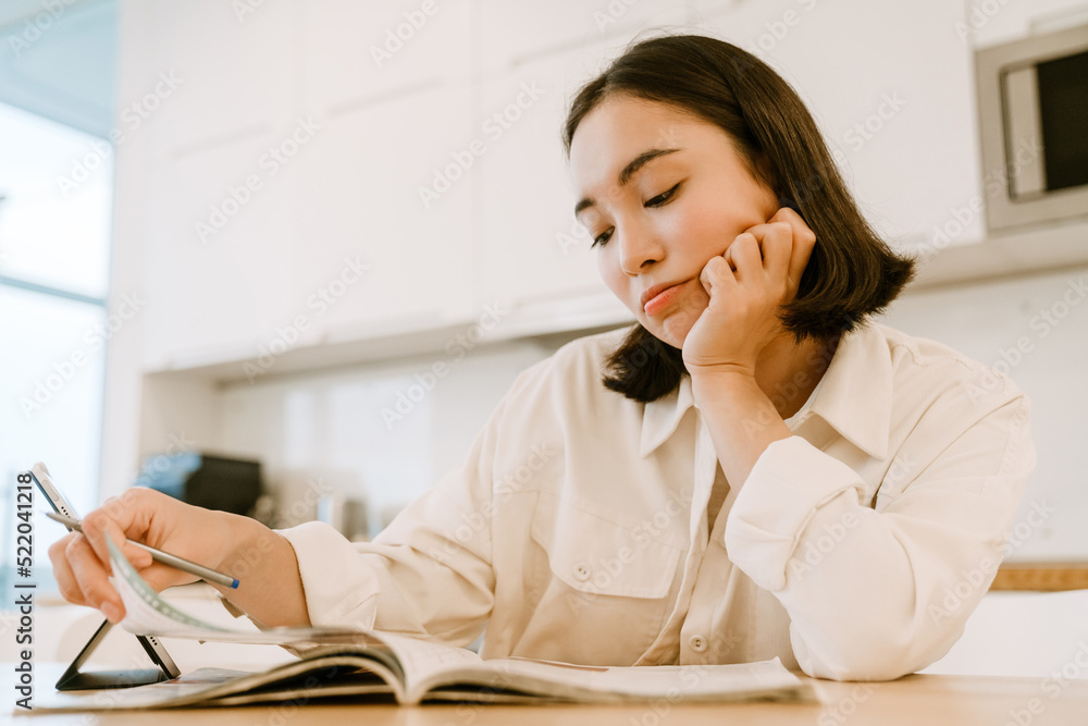 Young cute boring asian woman with tablet studying at home Young cute boring asian woman with tablet studying at home