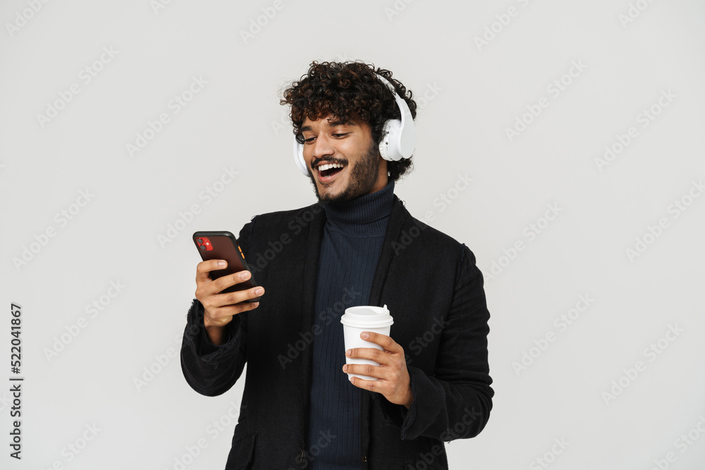 Young smiling indian man in headphones with coffee and phone Young smiling indian man in headphones with coffee and phone