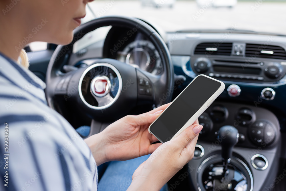 Cropped view of driver holding smartphone in blurred auto