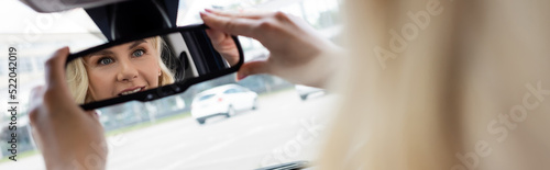 Blurred woman adjusting mirror in car, banner