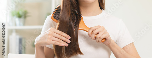 Tableau sur toile Health hair care, beauty makeup asian woman, girl holding hairbrush and brushing, combing her long straight hair looking at reflection in mirror in morning routine after salon treatment, hairstyle
