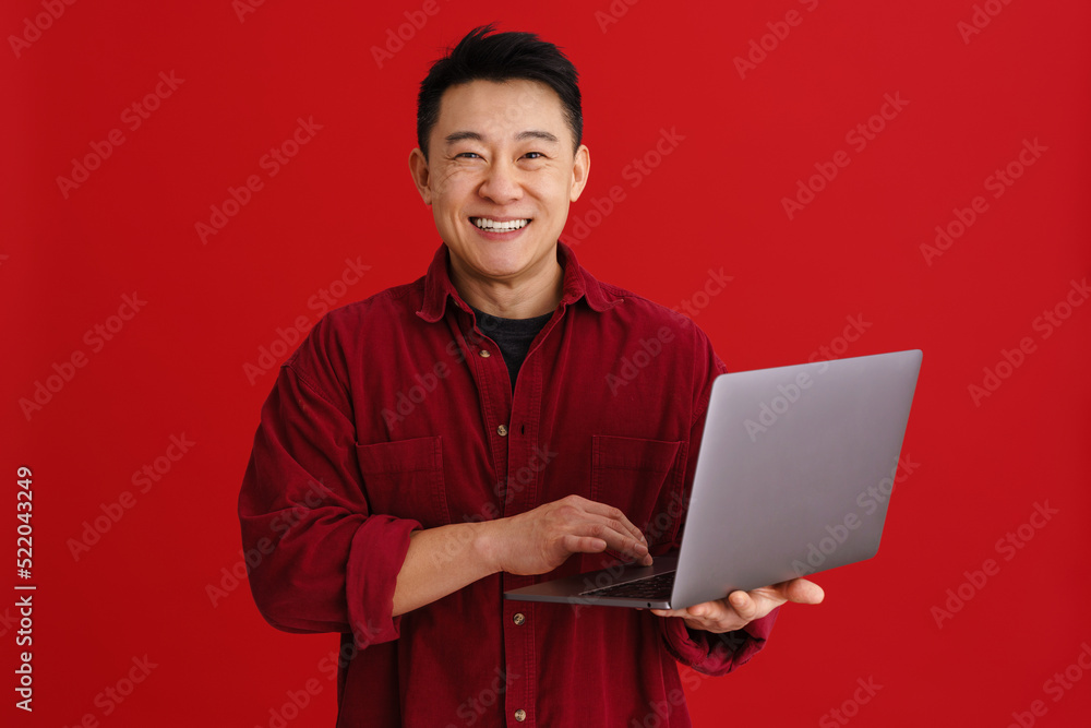 Asian young man wearing shirt laughing while using laptop Asian young man wearing shirt laughing while using laptop