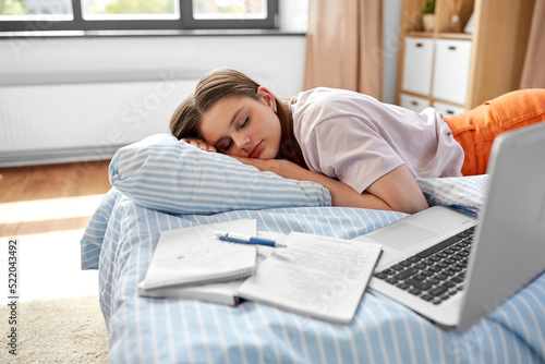 school, education and laziness concept - tired teenage student girl with laptop computer and notebooks sleeping on bed at home