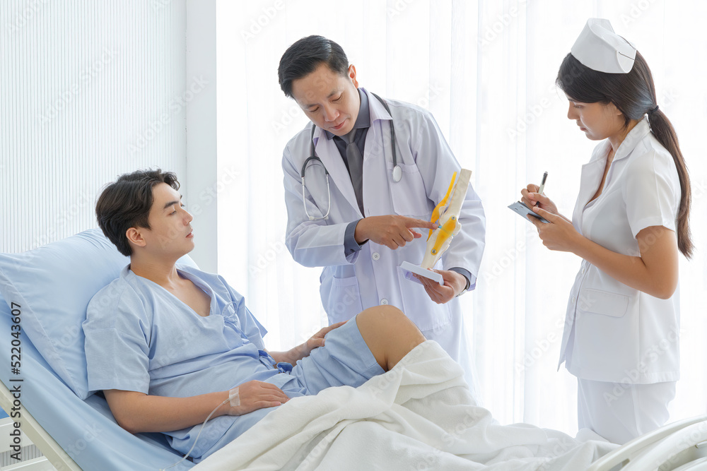 Orthopedic professional doctor and nurse interact with patient who lie on bed , Knee pain patient get treatment advice doctor in examination room.