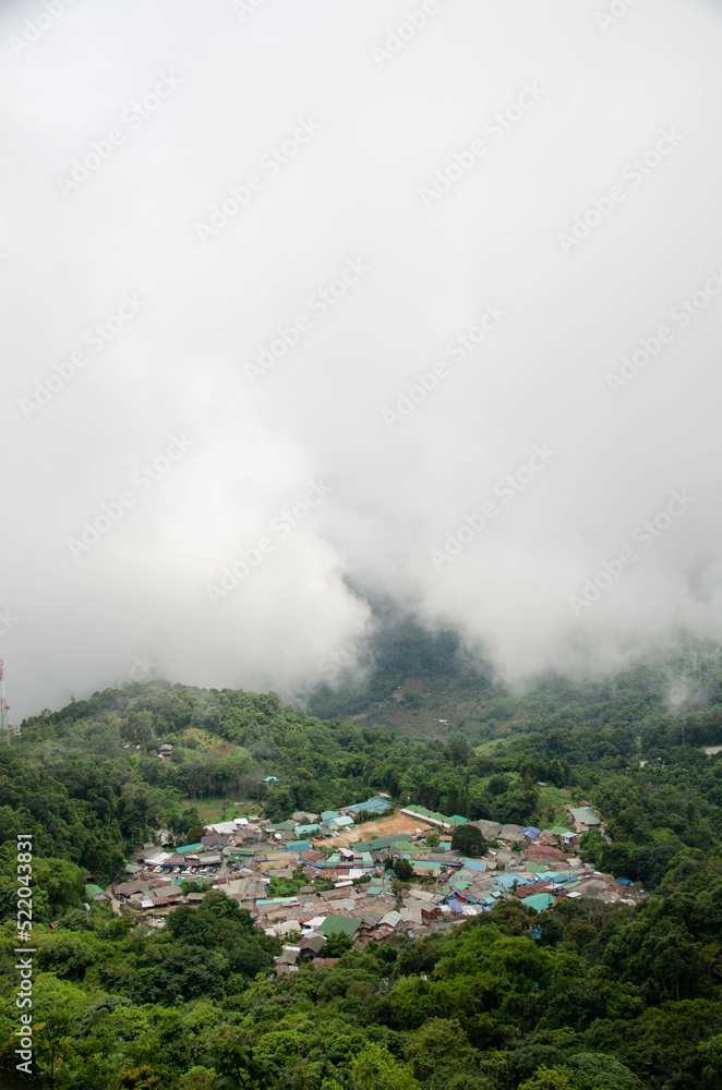 Fototapeta premium view of the doi pui local countryside village among the mountain hill range surround with mist fog above cloud sky