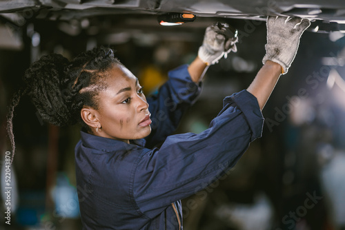 Canvastavla Black african woman mechanic staff worker work service under car in dirty garage