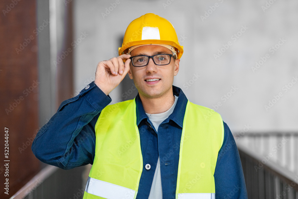 architecture, construction business and building concept - happy smiling male architect in helmet and safety west at office architecture, construction business and building concept - happy smiling male architect in helmet and safety west at office