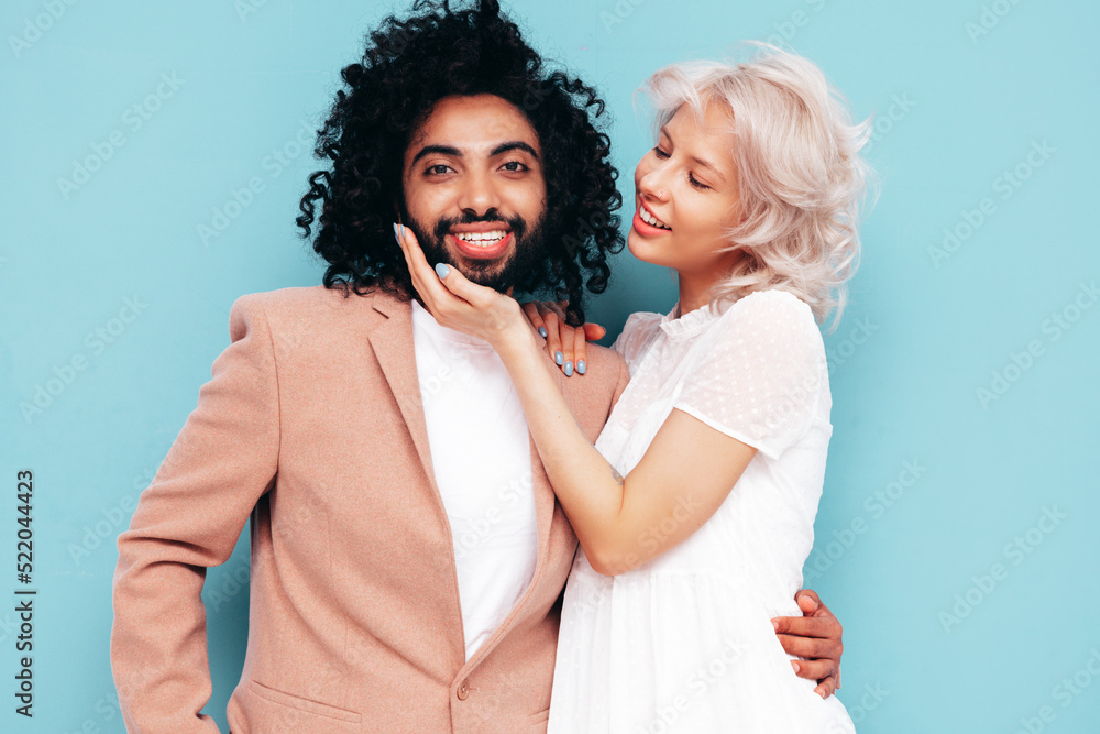 Smiling beautiful woman and her handsome boyfriend. Sexy cheerful multiracial family having tender moments on blue background in studio. Multiethnic models hugging. Embracing each other. Love concept Smiling beautiful woman and her handsome boyfriend. Sexy cheerful multiracial family having tender moments on blue background in studio. Multiethnic models hugging. Embracing each other. Love concept
