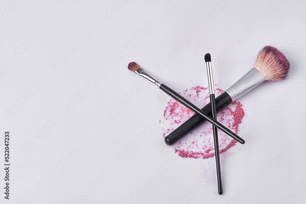 Top view pile of various makeup brushes. Round stain of cosmetic powder. Top view pile of various makeup brushes. Round stain of cosmetic powder.