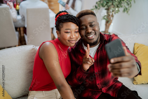 Cousins meet during Christmas for family dinner, man in red shirt takes selfie with beautiful woman with smartphone, they smile satisfied, happy