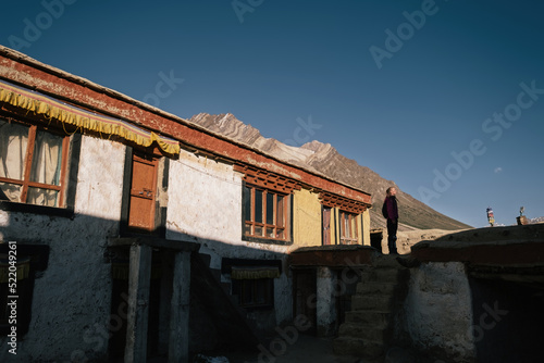 Woman traveler standing near Buddhist Tibetan monastery in Zanskar during sunset