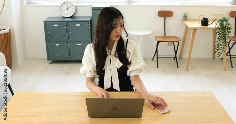 A Japanese woman checking smartphone by remote work in the small office A Japanese woman checking smartphone by remote work in the small office