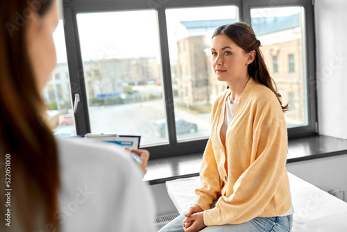 medicine  healthcare and people concept - female doctor with clipboard talking to woman patient at hospital