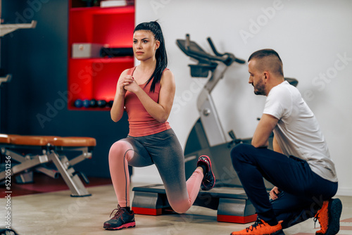 Fototapeta Naklejka Na Ścianę i Meble -  Woman Doing Workout For Legs With Coach In The Gym