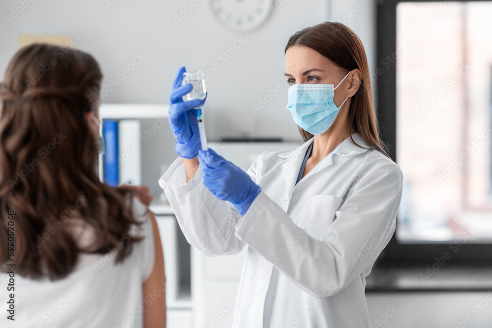 health, medicine and pandemic concept - female doctor or nurse wearing protective medical mask and gloves with syringe vaccinating patient at hospital health, medicine and pandemic concept - female doctor or nurse wearing protective medical mask and gloves with syringe vaccinating patient at hospital