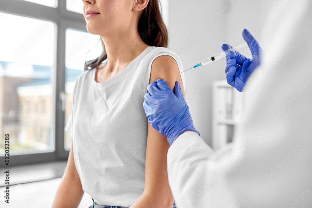 health, medicine and pandemic concept - female doctor or nurse wearing protective medical gloves with syringe vaccinating patient at hospital health, medicine and pandemic concept - female doctor or nurse wearing protective medical gloves with syringe vaccinating patient at hospital