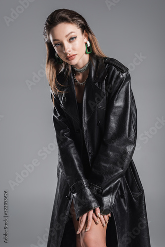 pretty young woman in trendy leather coat looking at camera isolated on grey
