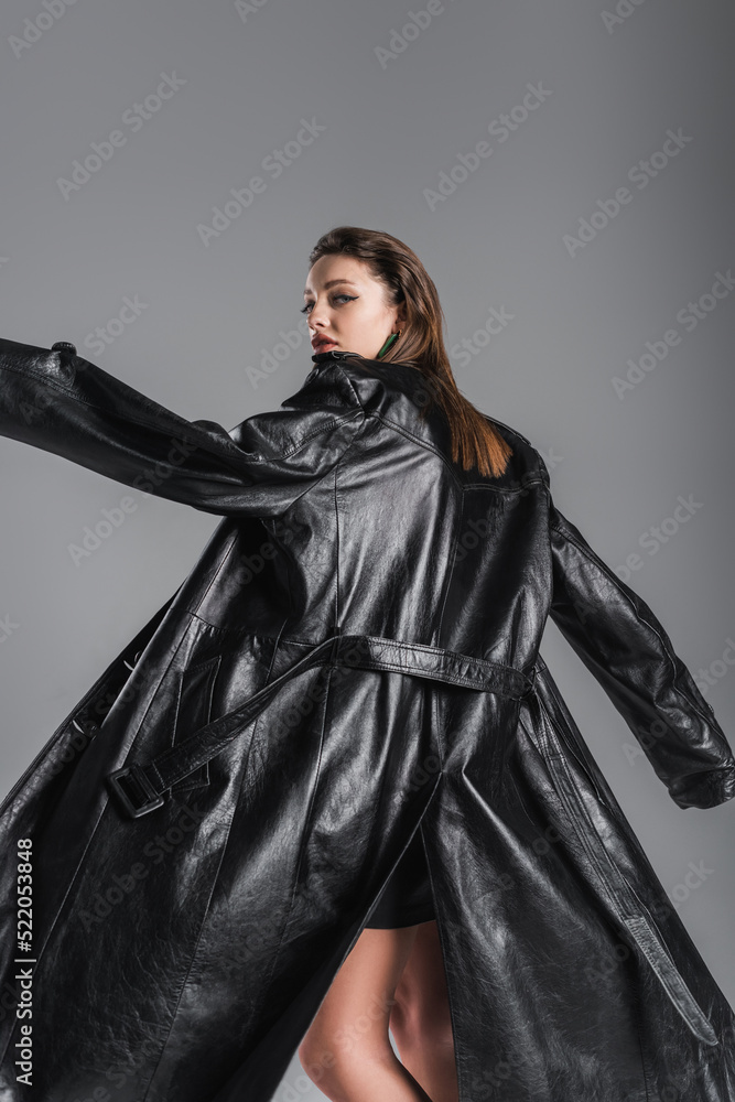 Naklejka premium young fashionable woman posing in black leather coat isolated on grey