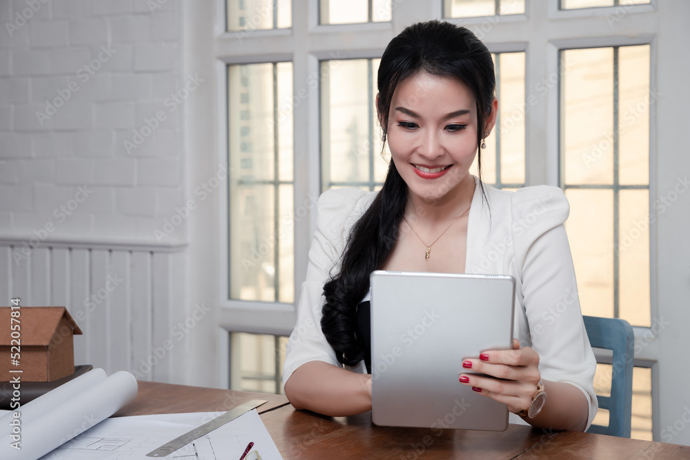 Beautiful young Asian working with tablet computer at office desk or co working space. Business successful concept. Asian businesswoman holding tablet and she smiled in a good mood. Beautiful young Asian working with tablet computer at office desk or co working space. Business successful concept. Asian businesswoman holding tablet and she smiled in a good mood.