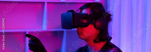 Man wearing virtual reality glasses is playing a 3D game with excitement, Bluetooth Remote Controller, VR, Future games, Gadgets, Technology, Red and blue background, VR game concept.