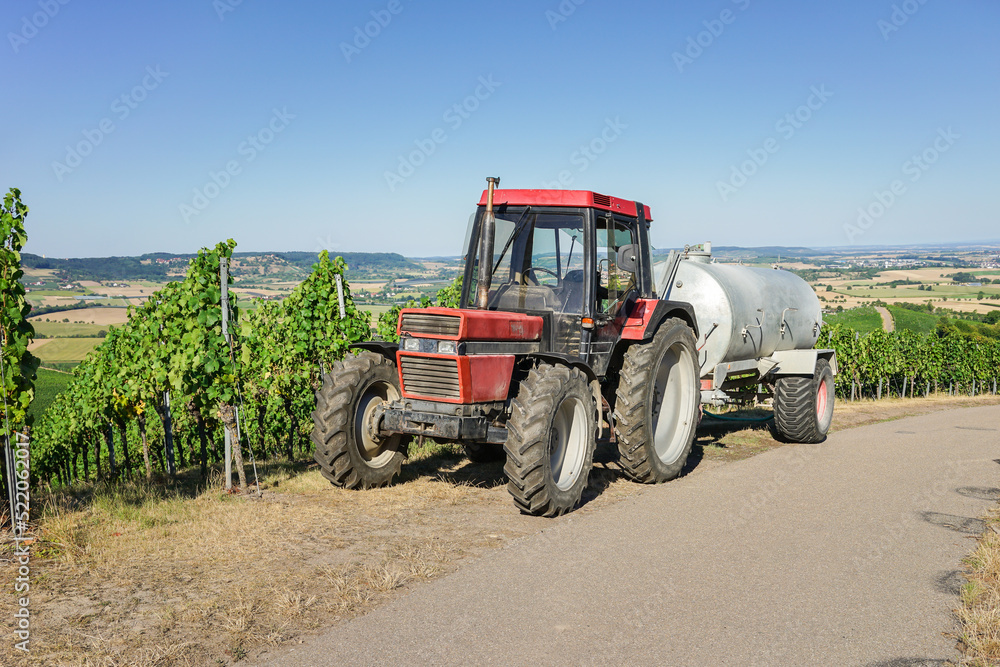 Obraz premium Traktor und Wassertank zum Bewässern der Weinreben in der Landwirtschaft