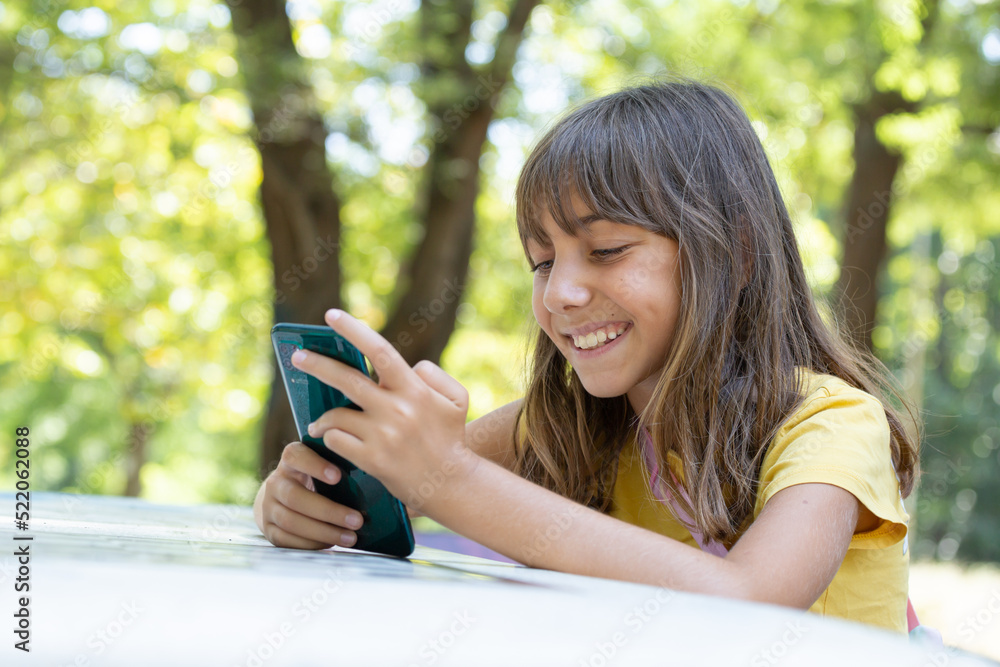 smiling girl communicates on smartphone in the park