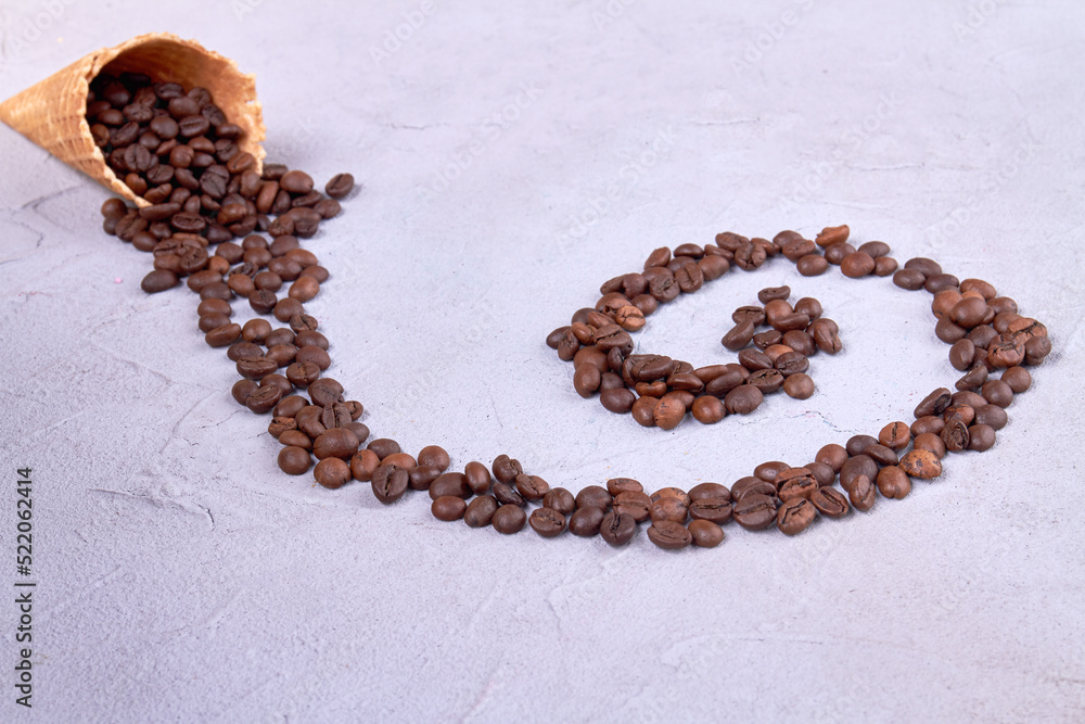 Ice cream cone with coffee beans in a swirl shape. White putty surface.